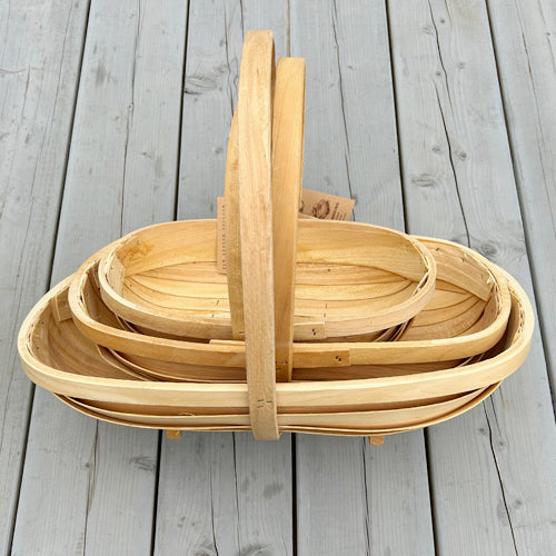 Stack of wooden gardening trug baskets with handles on a grey wooden table